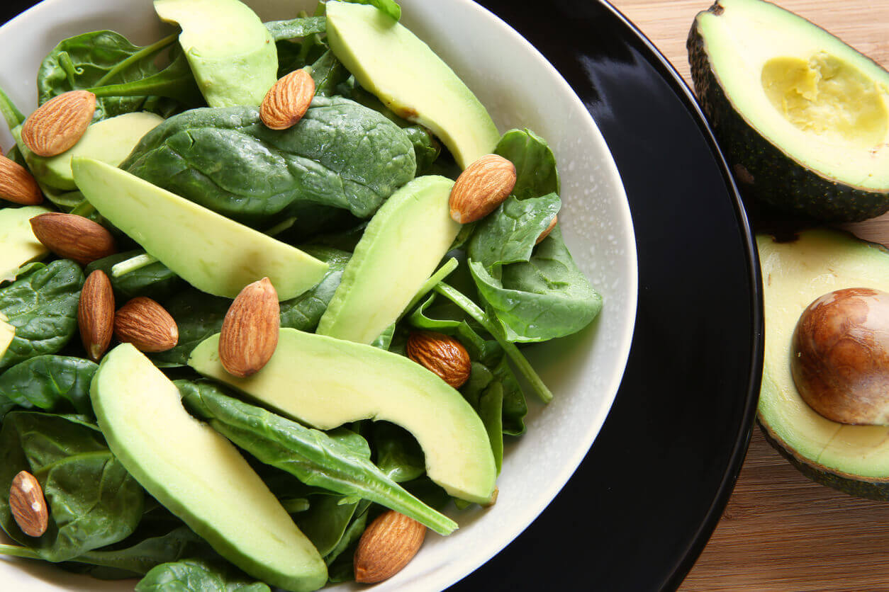 A salad made of spinach, avocado and almonds.