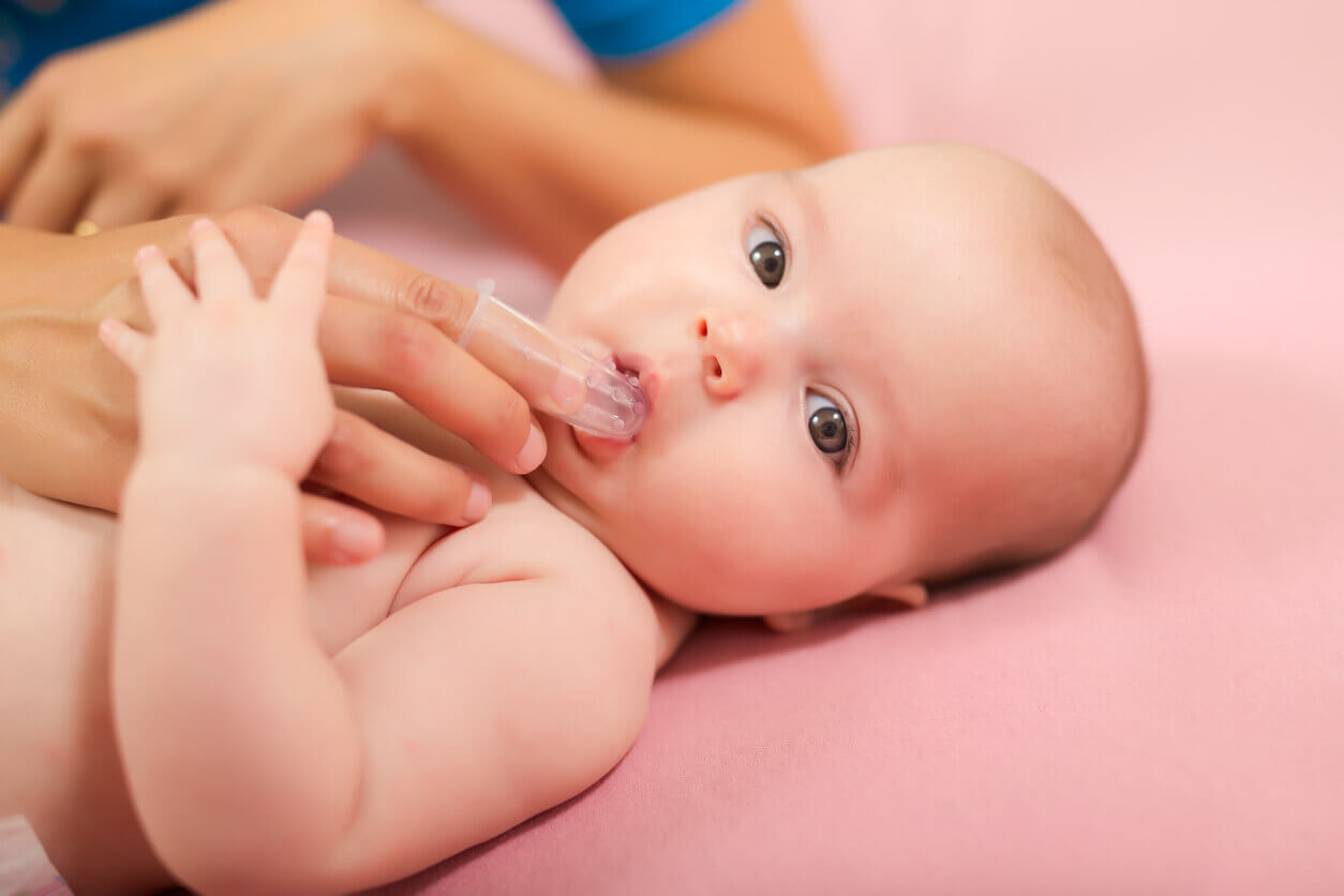 A mother using a silicone finger brush to clean her baby's mouth.