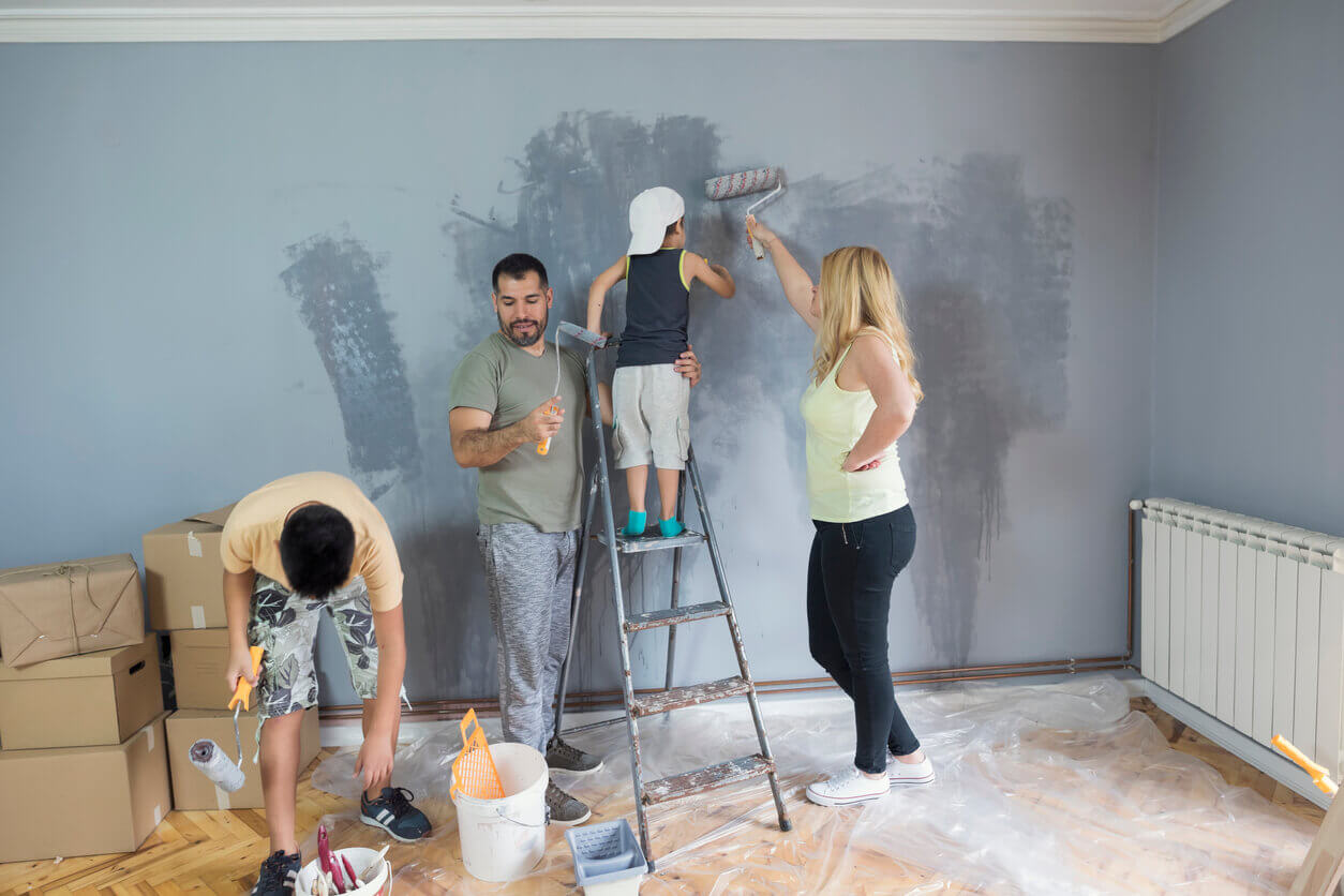 Perhe maalaa seiniä.