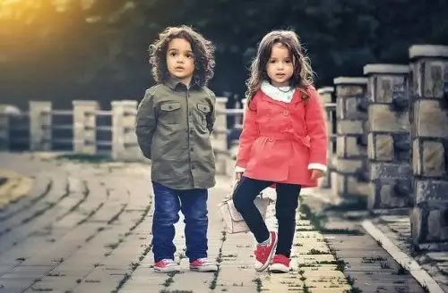 Two children standing on a bridge.