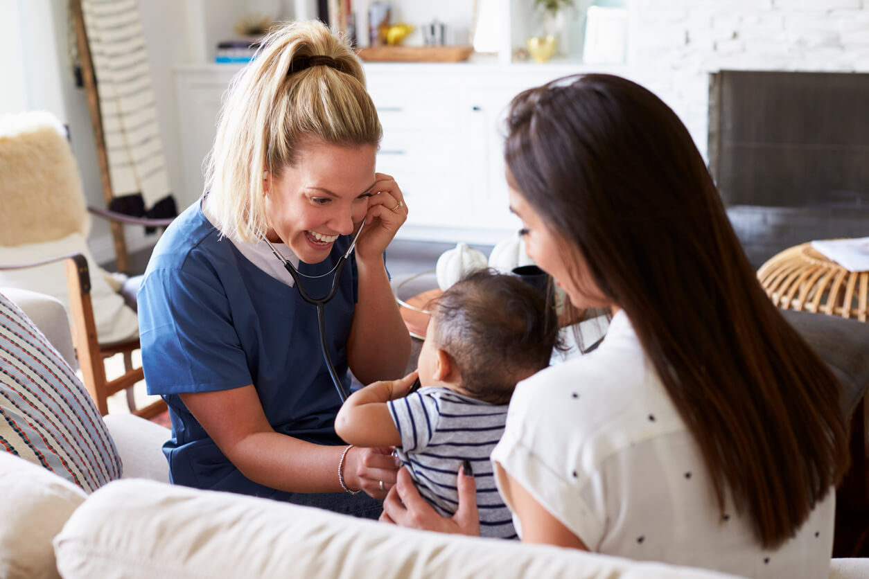 A family nurse practitioner listening to a baby's chest with a stethescope.