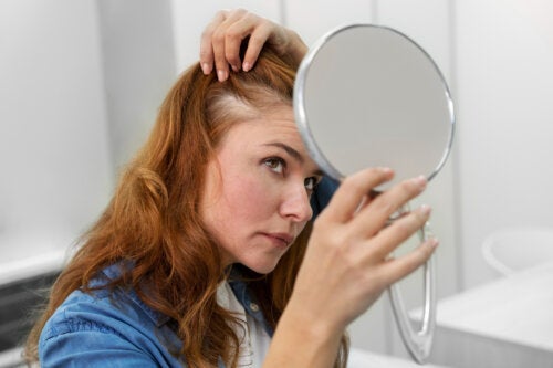 A menopausal woman looking at her hair in the mirror.
