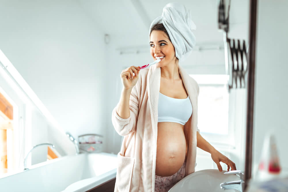 A pregnant woman brushing her teeth.