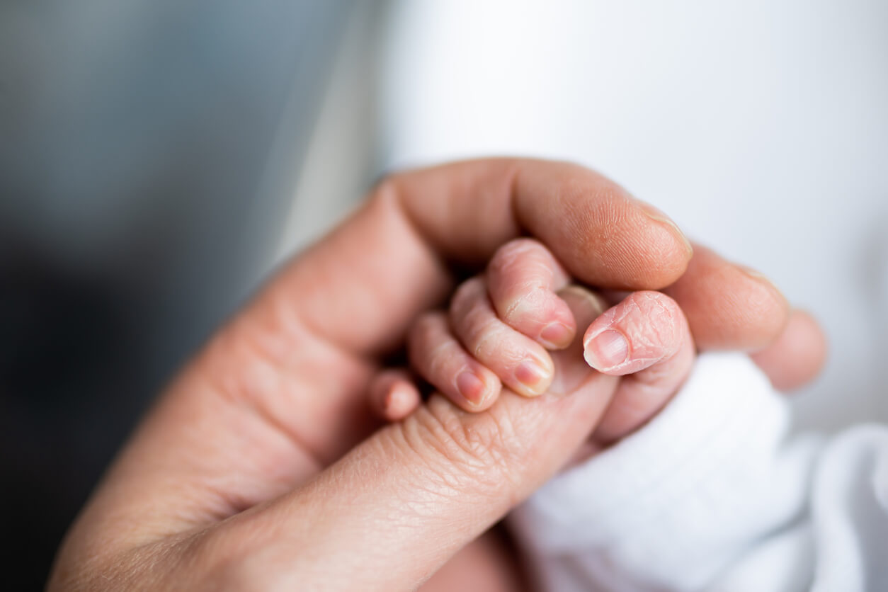 The hand of newborn baby who has just been born holding the finger of his father's hand.