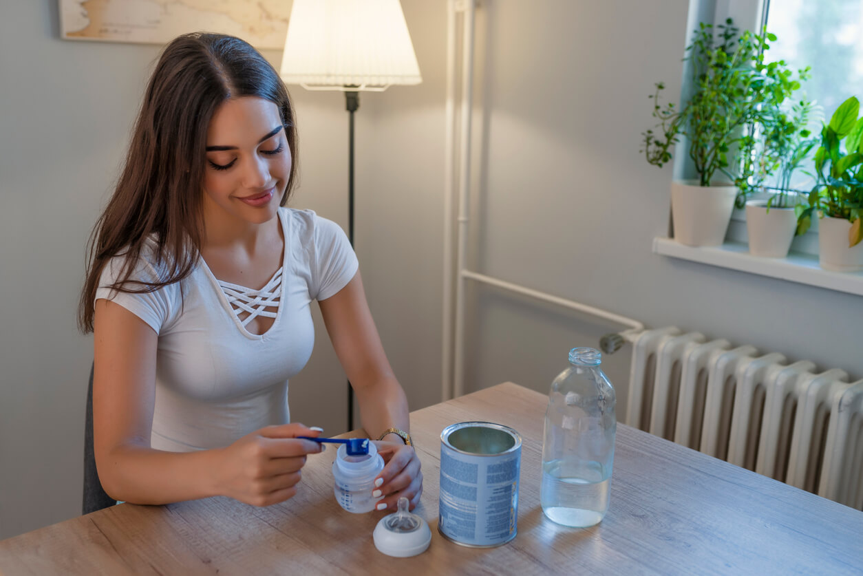 A woman preparing a bottle of baby formula.