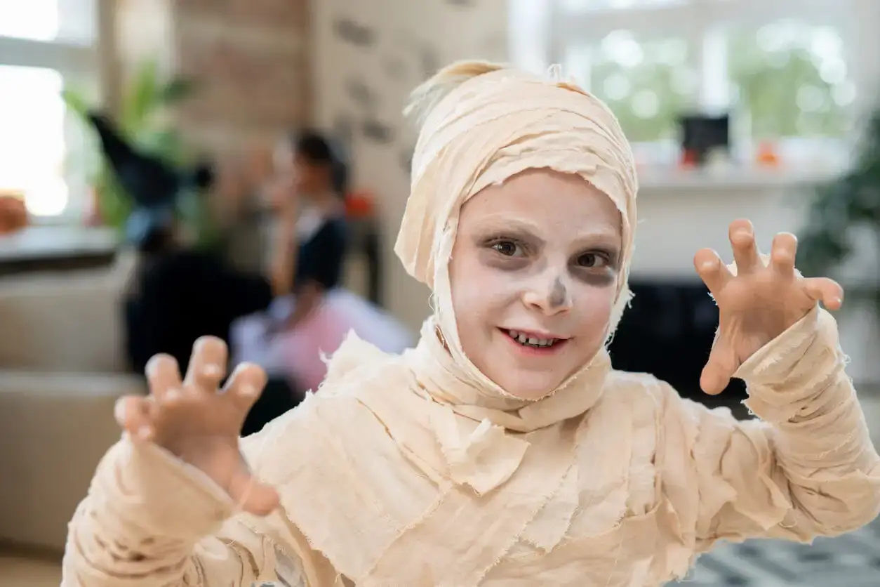 A young child dressed up as a mummy.