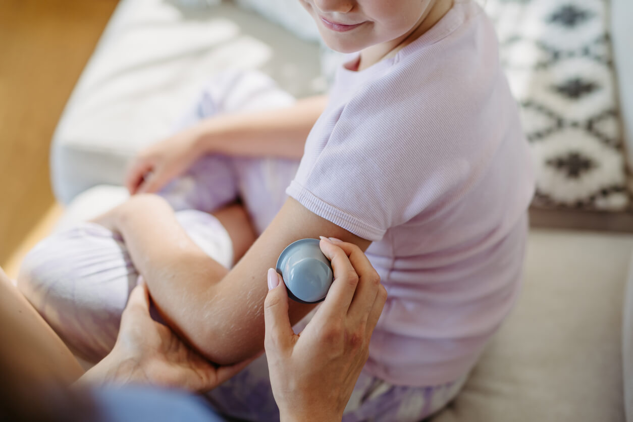 A close up of the application of a continuous glucose monitor sensor to the arm of a diabetic girl.