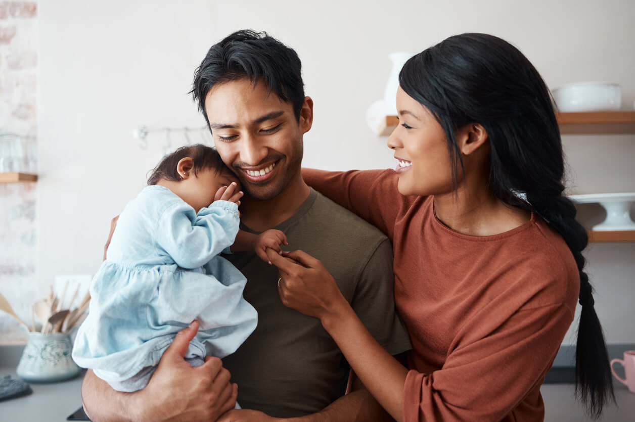Asian parents smiling while holding their baby girl.
