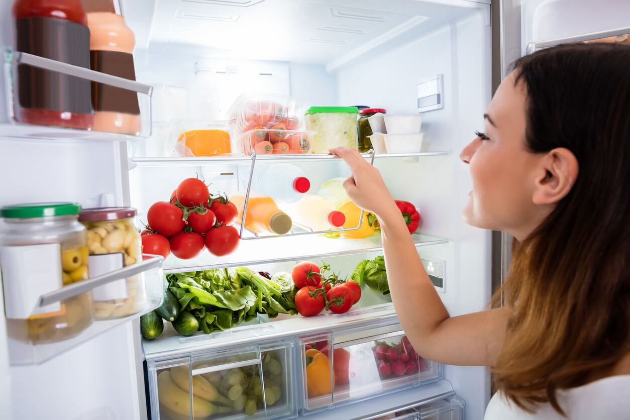 A woman taking advantage of less-used spaces in her fridge.