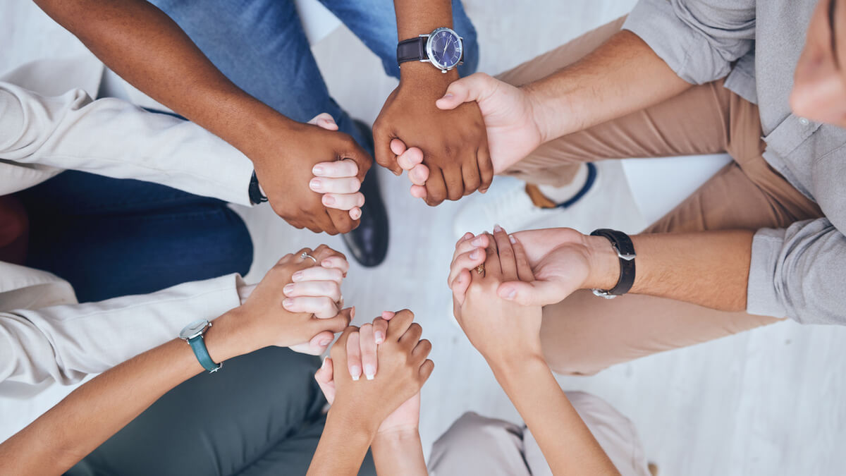People sitting in a circle holding hands.