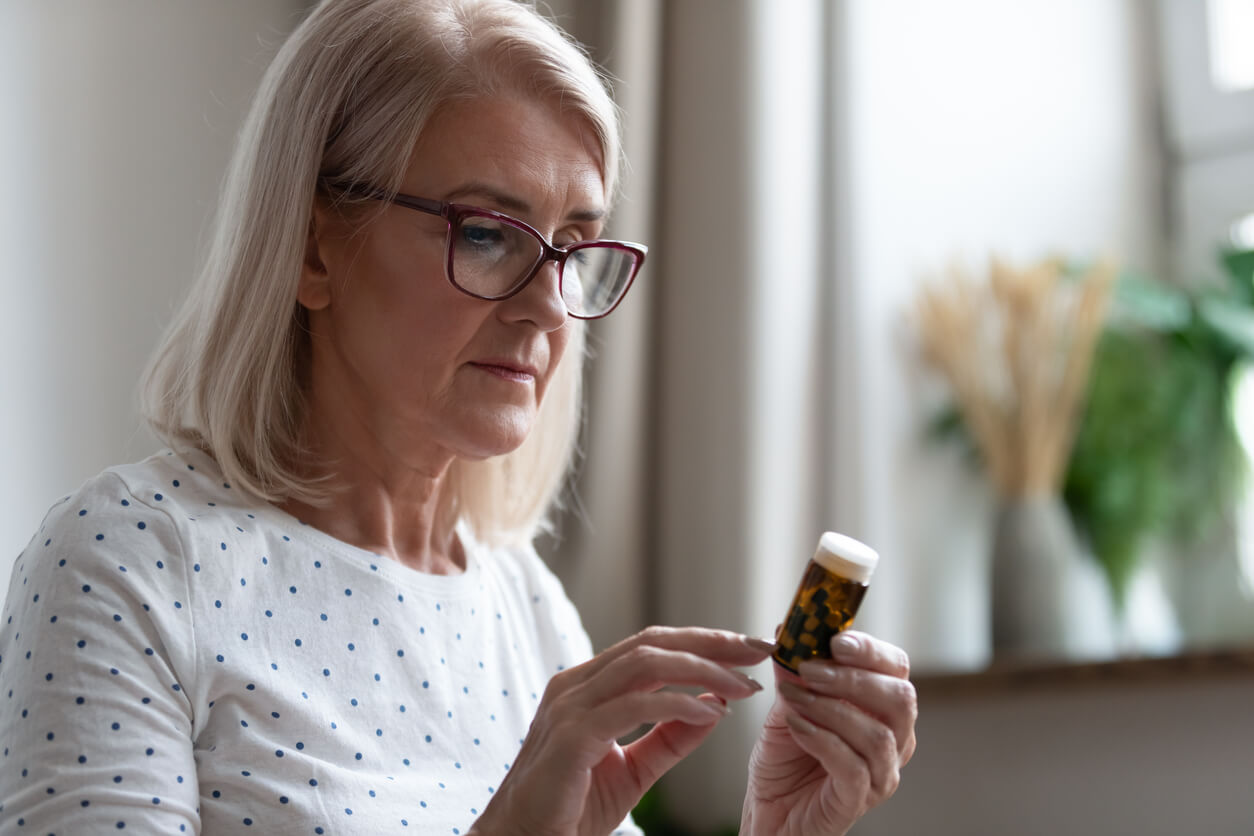 An older woman reading the indications on a bottle of medical cbd.