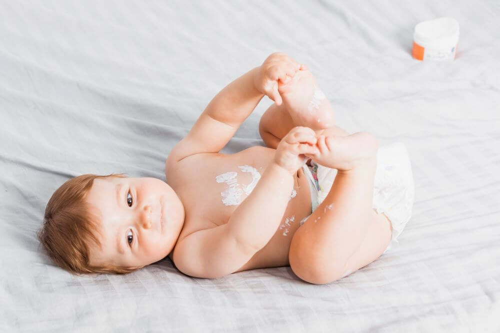 A baby with a smiley face on his belly made with diaper rash cream.